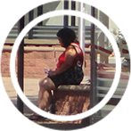Circular photo of a lady waiting for a bus sitting on bricks