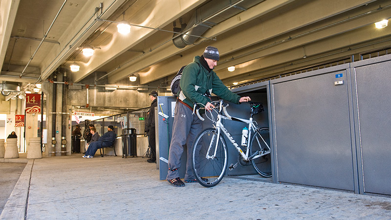 A man putting his bike into a bike locker